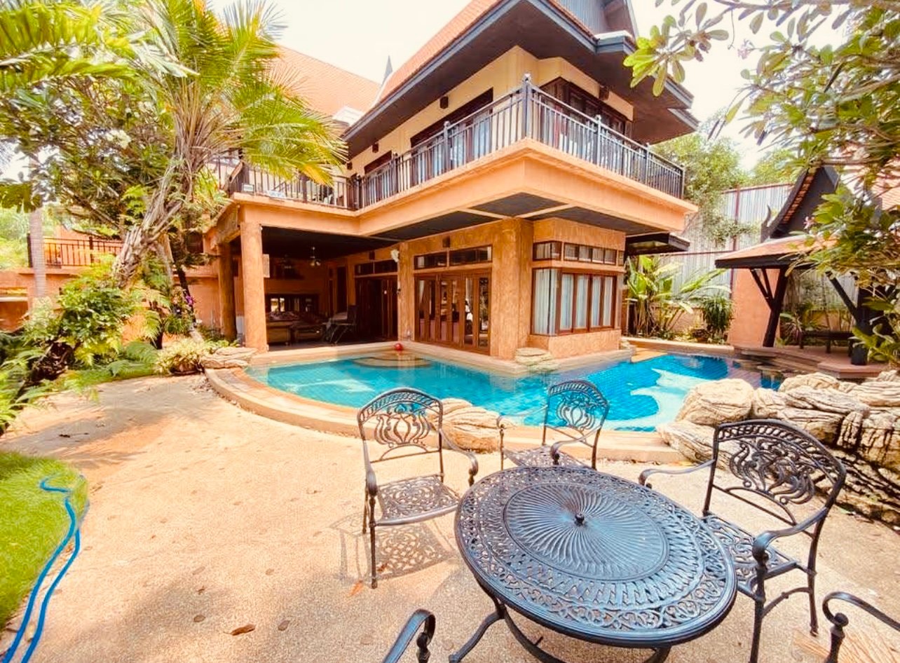 Two story tropical pool Villa in Pattaya with private swimming pool, outdoor seat, lush, and Thai style architecture.